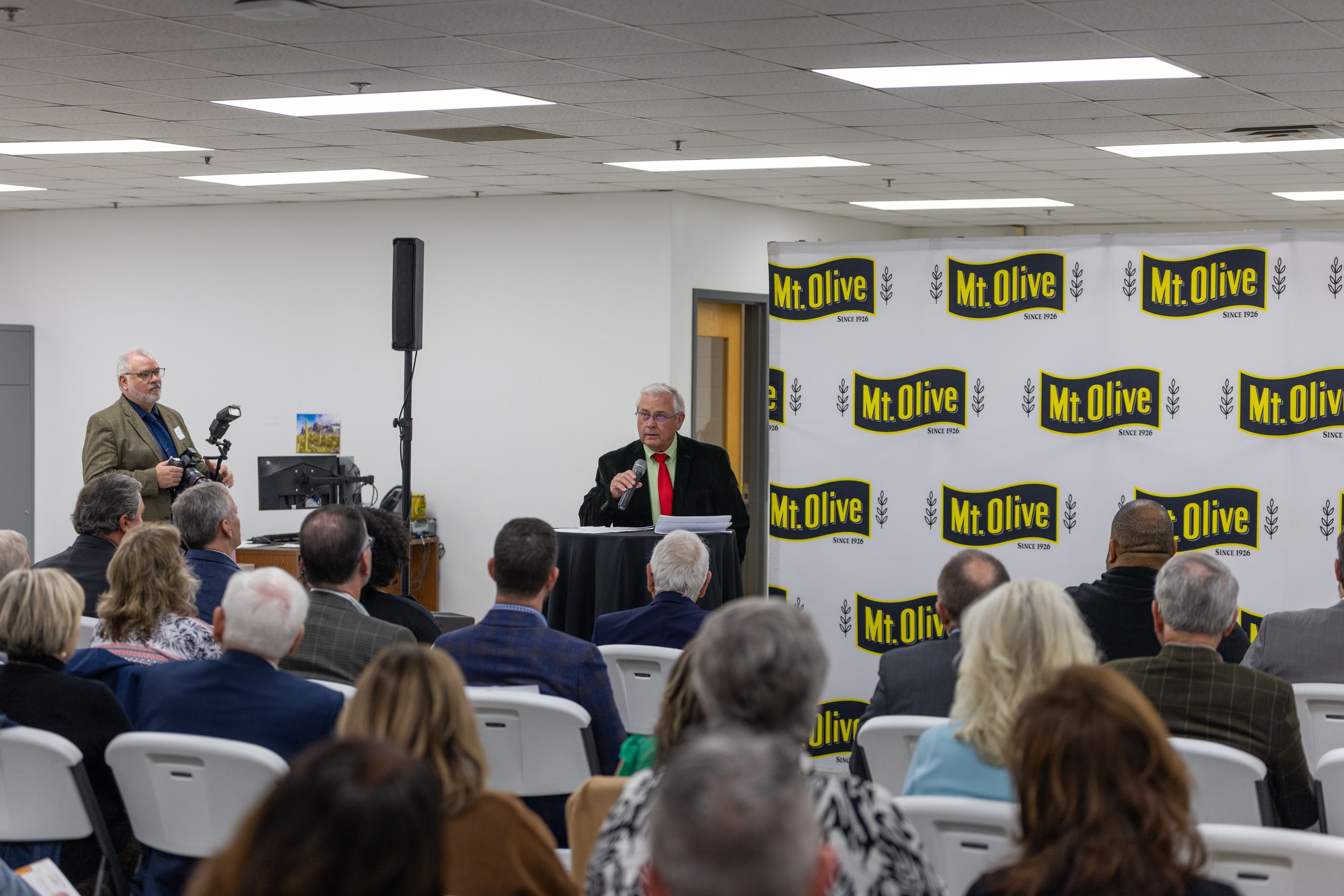 Commissioner Daughtery stands at a podium addressing the crowd.